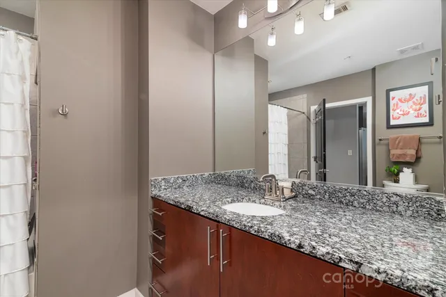 a bathroom with a granite countertop sink and a mirror