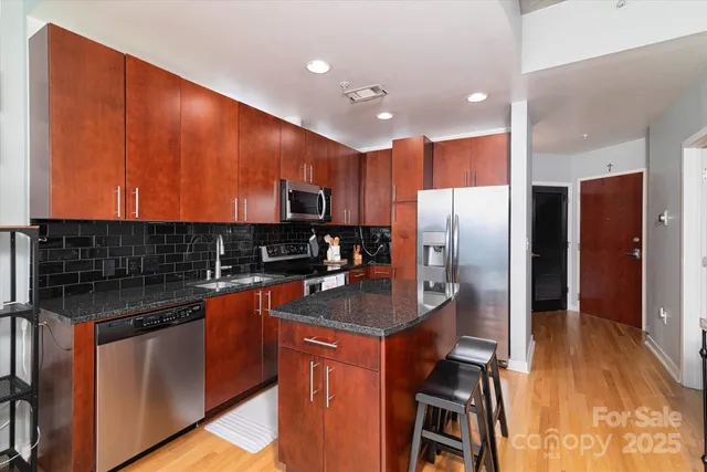 a kitchen with stainless steel appliances granite countertop a refrigerator a stove and a sink