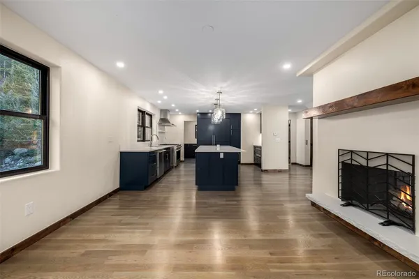 a view of an empty room with wooden floor and a fireplace
