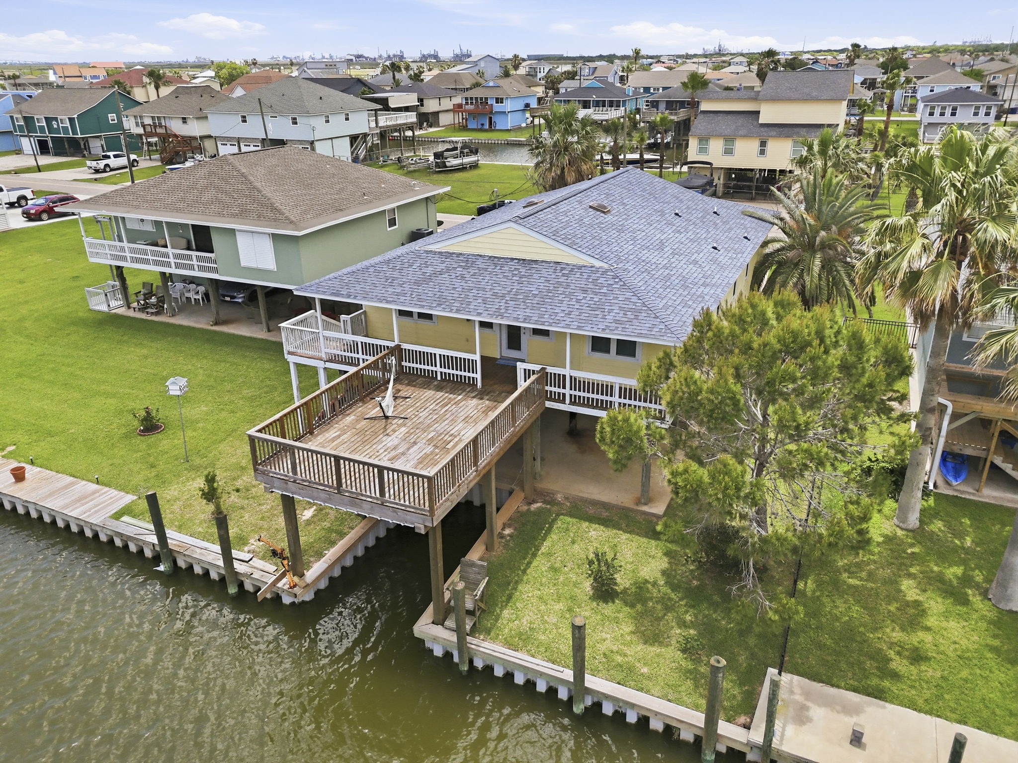 119 Sand Shoals Road Freeport, TX 77541 - Photo 8 of 34 Side aerial — upper sun deck with railing, lower covered porch off the main living area, full canal frontage, and bulkheaded waterline.