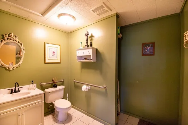a bathroom with a toilet sink vanity granite and mirror