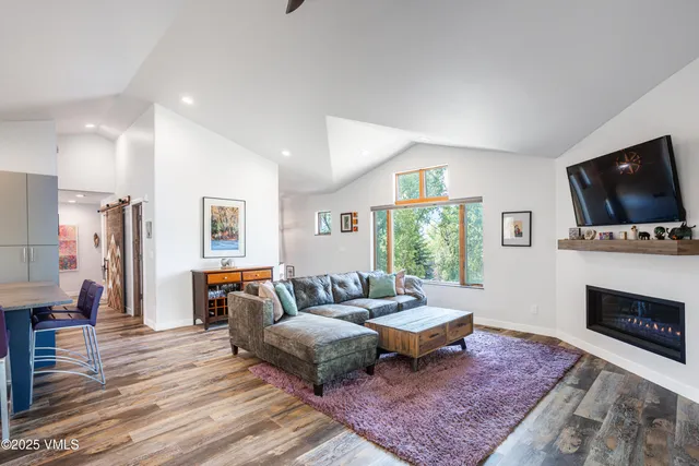 a living room with furniture wooden floor and kitchen view