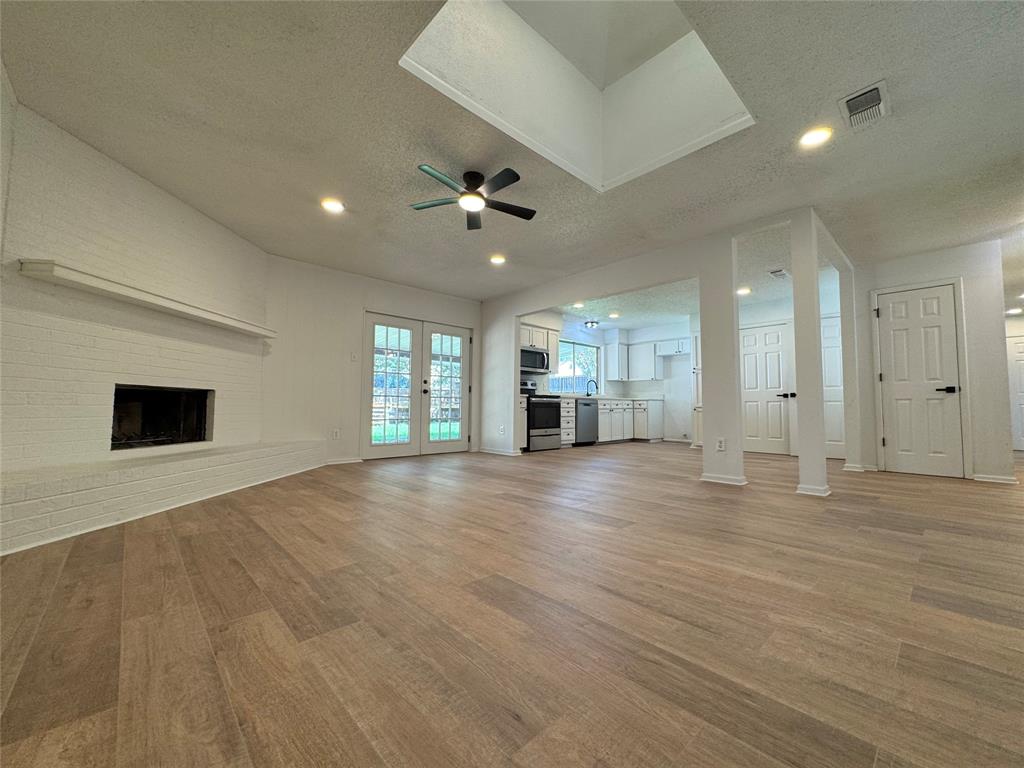 6645 Starnes Road Watauga, TX 76148 - Photo 4 of 18 Spacious living area featuring wood-finish flooring, a white brick fireplace, and dual French doors