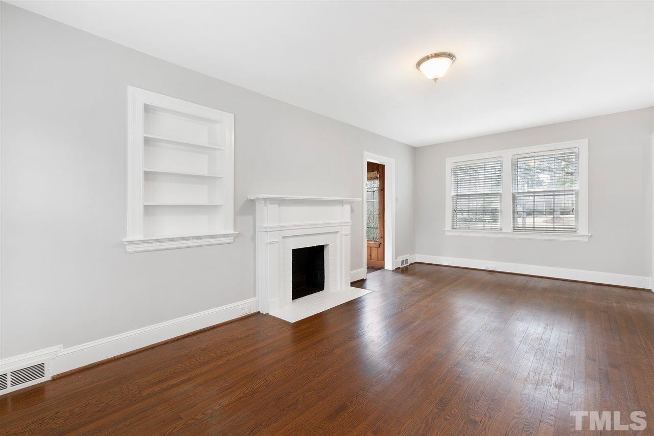 2115 Reaves Drive Raleigh, NC 27608 - Photo 6 of 26 an empty room with wooden floor fireplace and windows