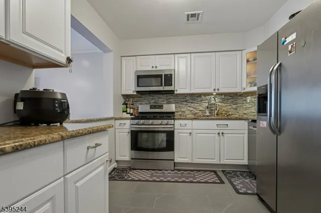 a kitchen with granite countertop a refrigerator stove and microwave