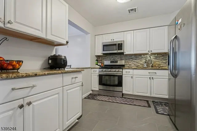 a kitchen with stainless steel appliances white cabinets and a stove top oven