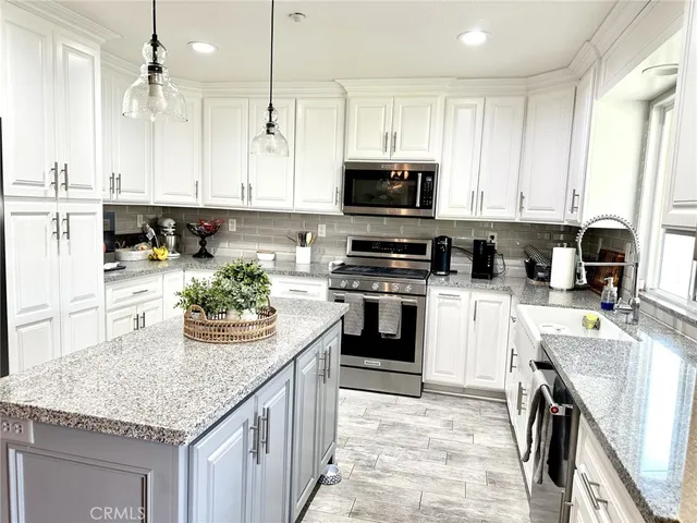 a kitchen with kitchen island granite countertop stainless steel appliances a stove sink microwave and cabinets