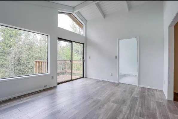 an empty room with wooden floor and windows