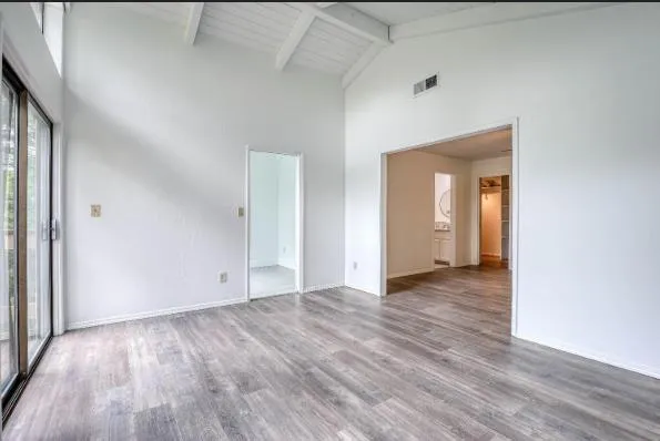a view of an empty room with wooden floor and a window