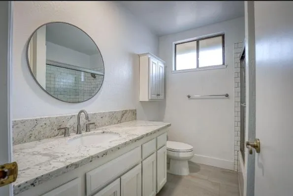 a bathroom with a granite countertop toilet a sink and a mirror