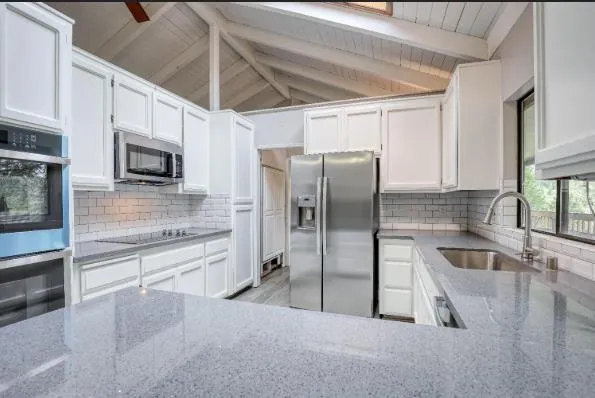 a kitchen with stainless steel appliances granite countertop a refrigerator a stove and a sink with wooden floors