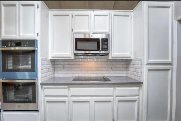 a kitchen with granite countertop white cabinets and stainless steel appliances