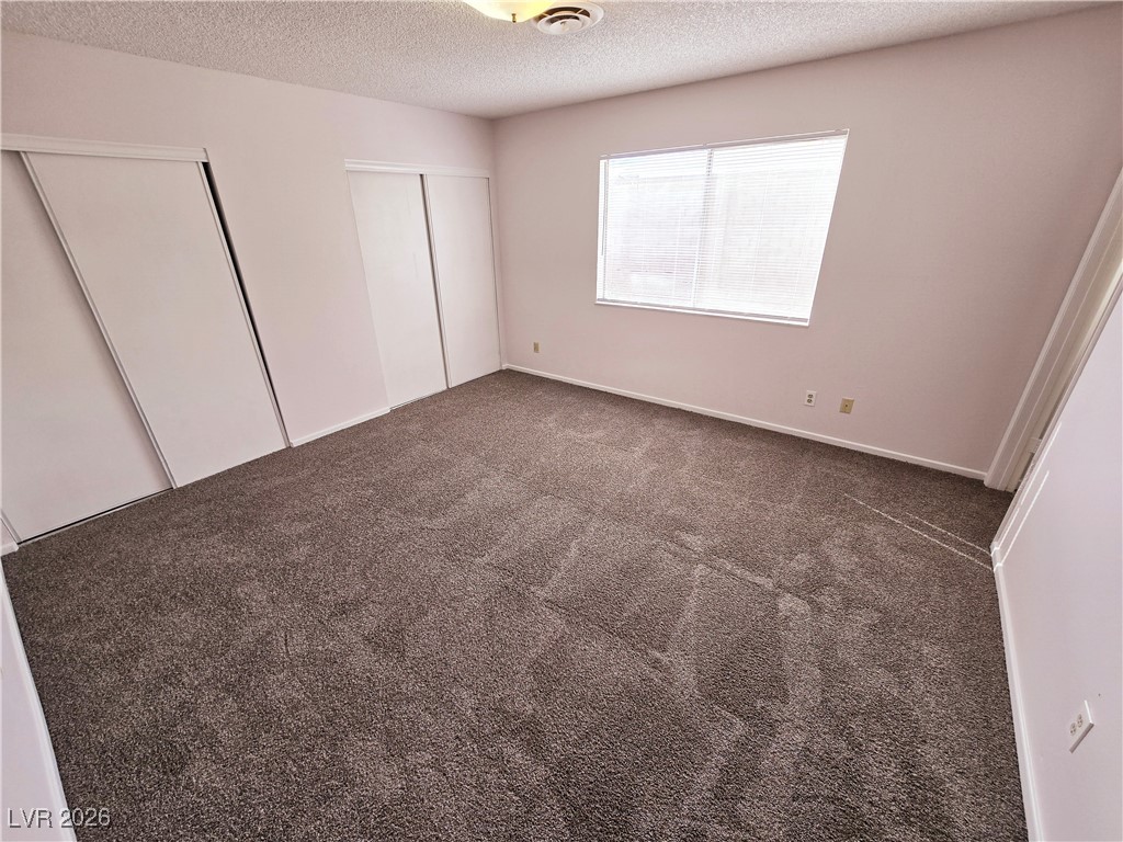 1108 Meadbrook Street Las Vegas, NV 89110 - Photo 16 of 41 Unfurnished bedroom with dark carpet, a textured ceiling, and multiple closets