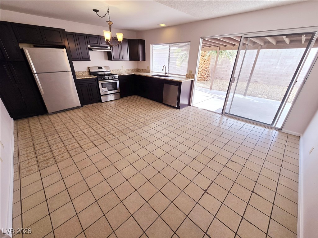 1108 Meadbrook Street Las Vegas, NV 89110 - Photo 27 of 41 Kitchen featuring stainless steel appliances, light countertops, decorative light fixtures, a chandelier, and under cabinet range hood