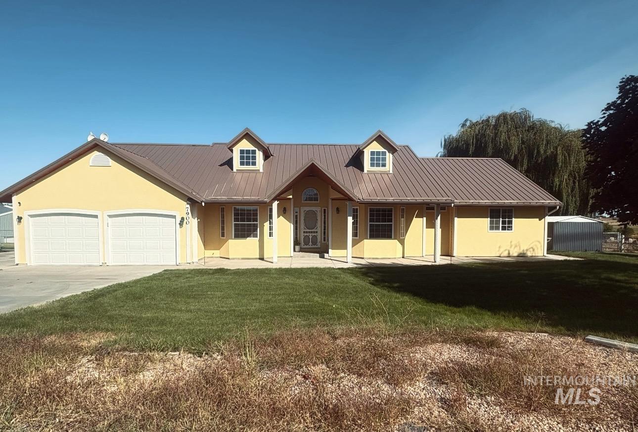 7900 Labor Camp Road Caldwell, ID 83607 - Photo 1 of 45 Yellow exterior with a brown metal roof, dual garage doors, a covered entry porch, and twin dormer windows