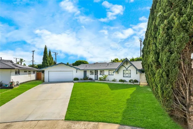 a view of a white house with a big yard plants and large trees