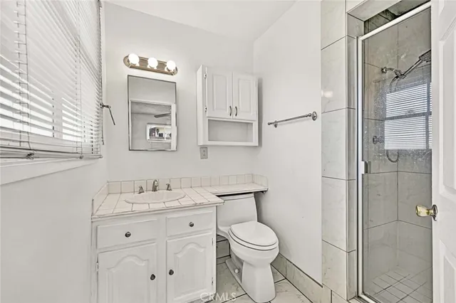 a bathroom with a granite countertop sink toilet and shower