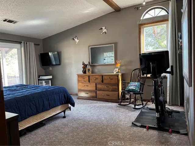 a bedroom with a bed and a flat tv screen on the dresser