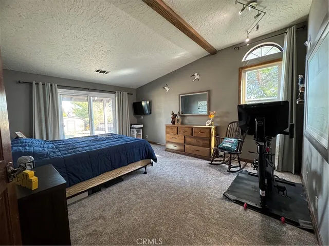 a spacious bedroom with a bed a dresser and flat screen tv