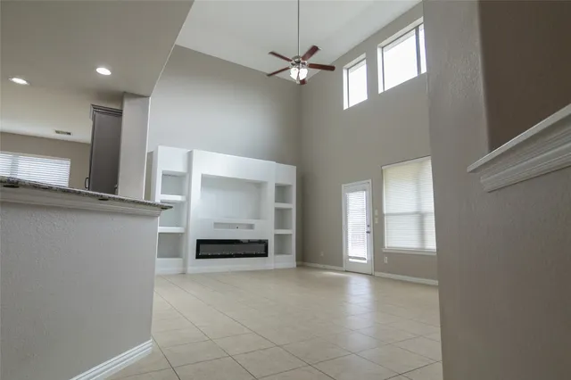 an empty room with windows and chandelier fan