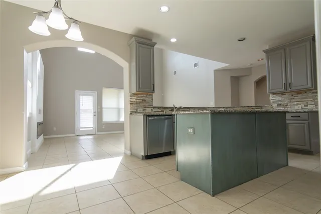 an empty room with chandelier fan and windows