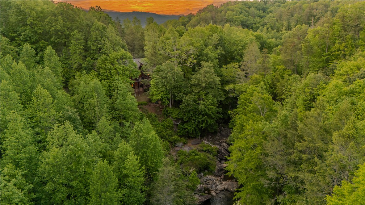 102 State Rd S-39-143 Sunset, SC 29685 - Photo 5 of 47 Nestled amidst lush greenery, a secluded cabin overlooks a serene stream, offering ultimate privacy.