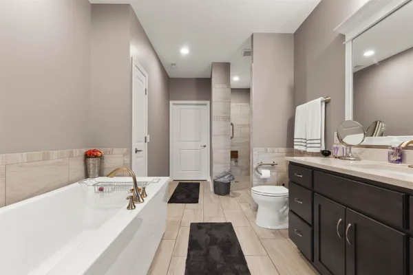 a large white tub sitting next to a white toilet