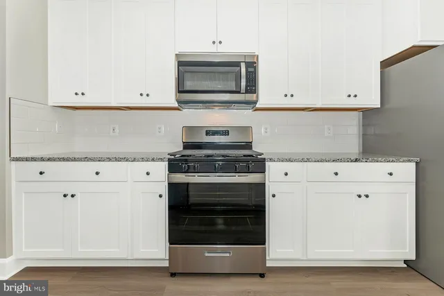 a kitchen with granite countertop white cabinets and stainless steel appliances