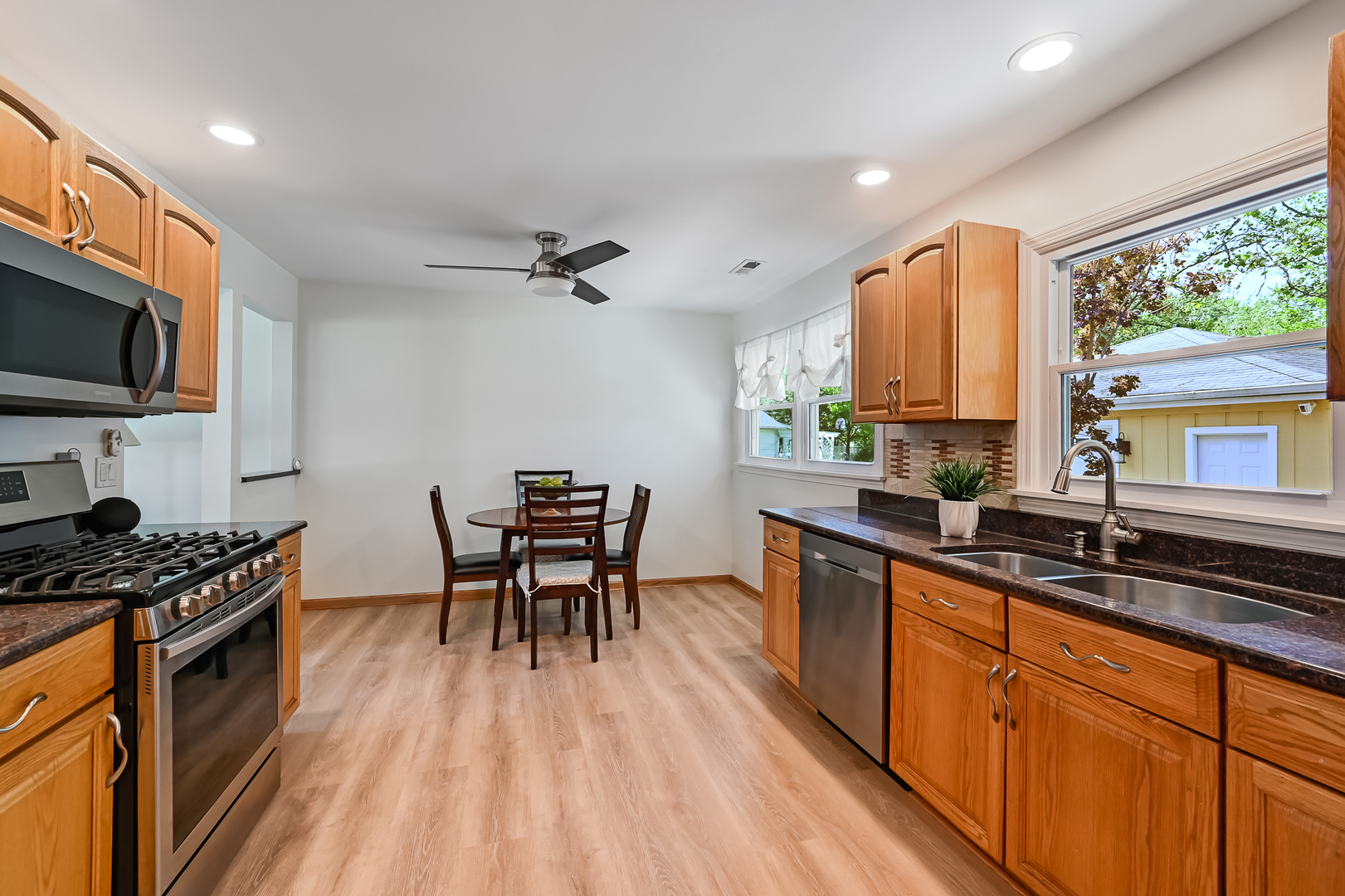 330 Village Road Willowbrook, IL 60527 - Photo 6 of 19 a kitchen with stainless steel appliances granite countertop a stove top oven a sink a dining table and chairs with wooden floor