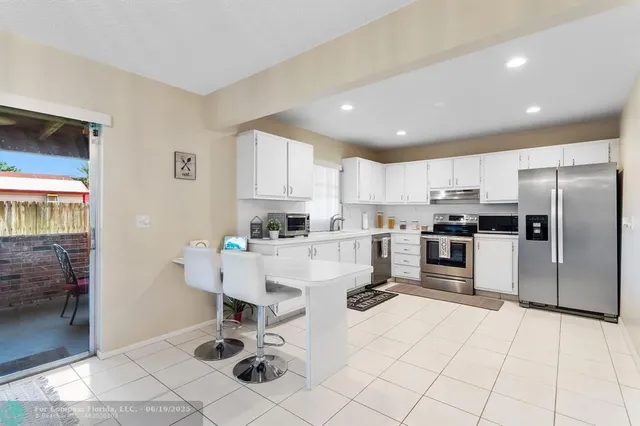 a kitchen with stainless steel appliances kitchen island granite countertop a refrigerator and cabinets