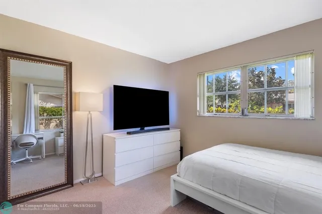a bedroom with bed and a flat tv screen on dresser