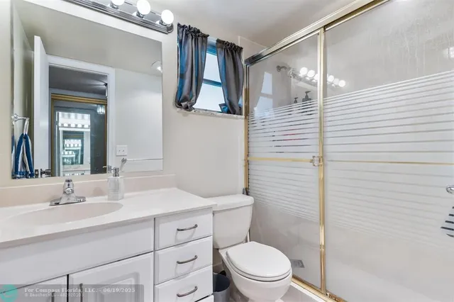 a bathroom with a sink a toilet a mirror and shower