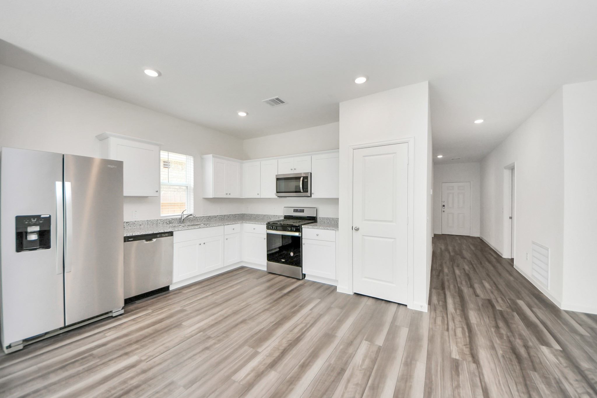 1812 Corsica Crk Lane Rosharon, TX 77583 - Photo 14 of 48 a kitchen with granite countertop a refrigerator oven a sink dishwasher and white cabinets with wooden floor