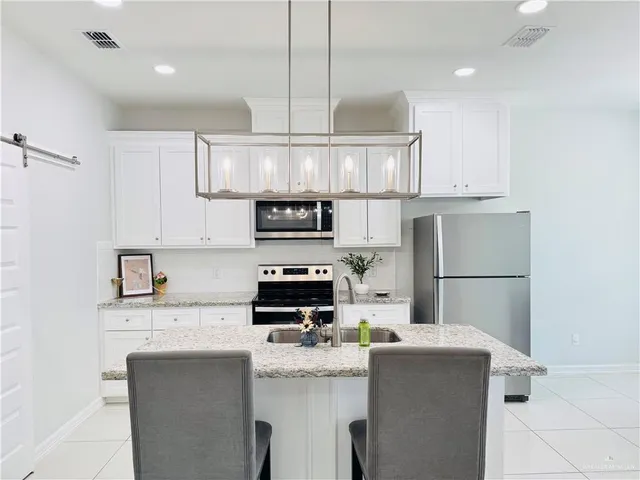 a kitchen with a sink a refrigerator a stove and white cabinets