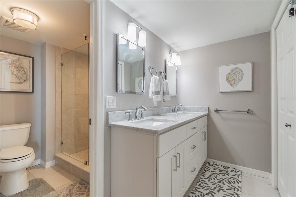 13650 Gulf Boulevard, Unit 402 Madeira Beach, FL 33708 - Photo 17 of 44 a spacious bathroom with a granite countertop sink a toilet and a mirror