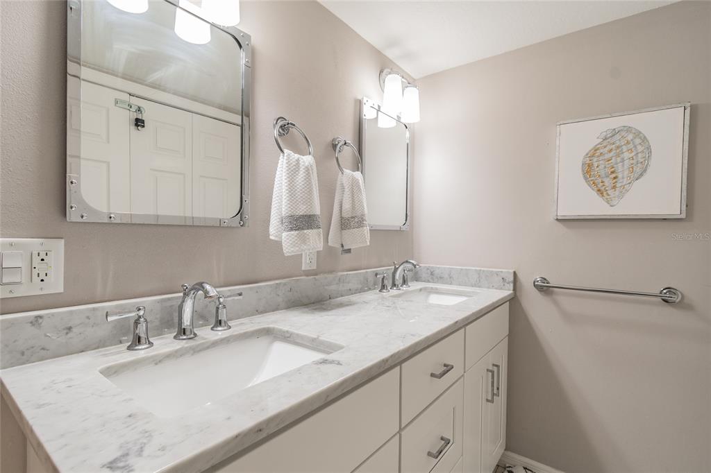 13650 Gulf Boulevard, Unit 402 Madeira Beach, FL 33708 - Photo 18 of 44 a bathroom with a granite countertop sink and a mirror
