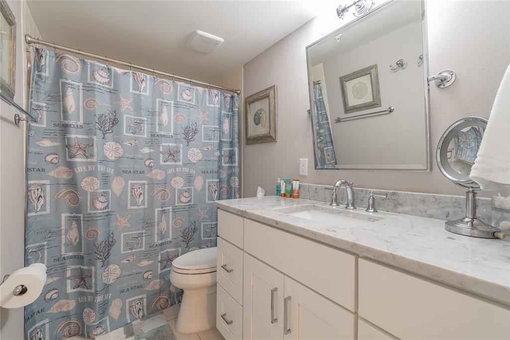 13650 Gulf Boulevard, Unit 402 Madeira Beach, FL 33708 - Photo 23 of 44 a bathroom with a granite countertop toilet sink and mirror