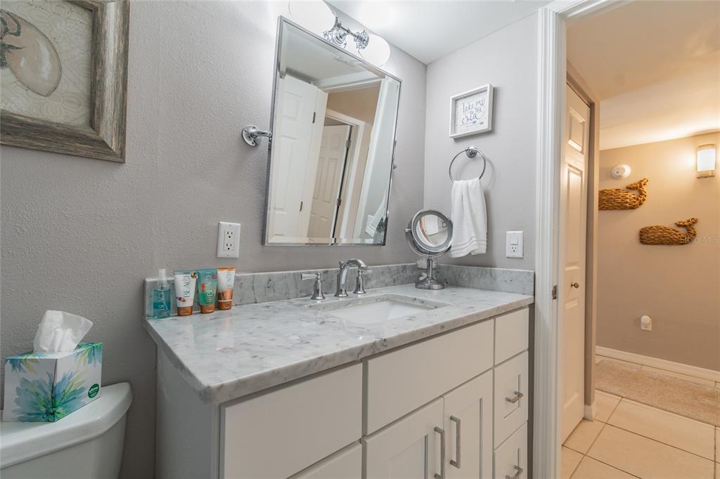 13650 Gulf Boulevard, Unit 402 Madeira Beach, FL 33708 - Photo 24 of 44 a bathroom with a granite countertop sink and a mirror