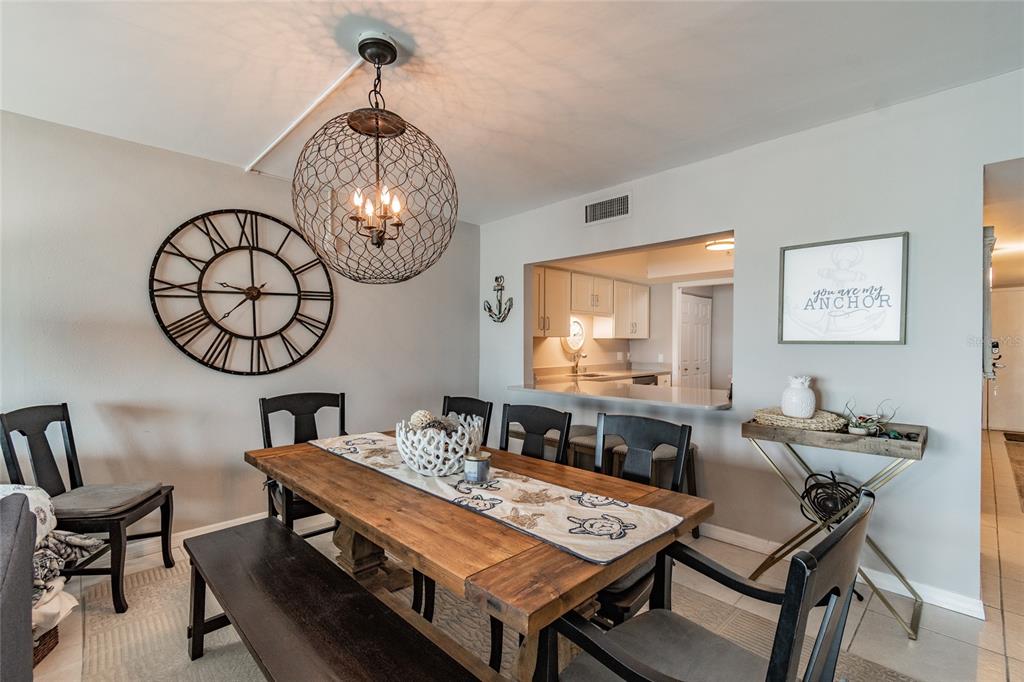 13650 Gulf Boulevard, Unit 402 Madeira Beach, FL 33708 - Photo 9 of 44 a view of a dining room with furniture a chandelier and wooden floor