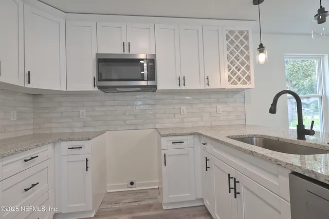 a kitchen with kitchen island granite countertop a sink a counter space appliances and cabinets