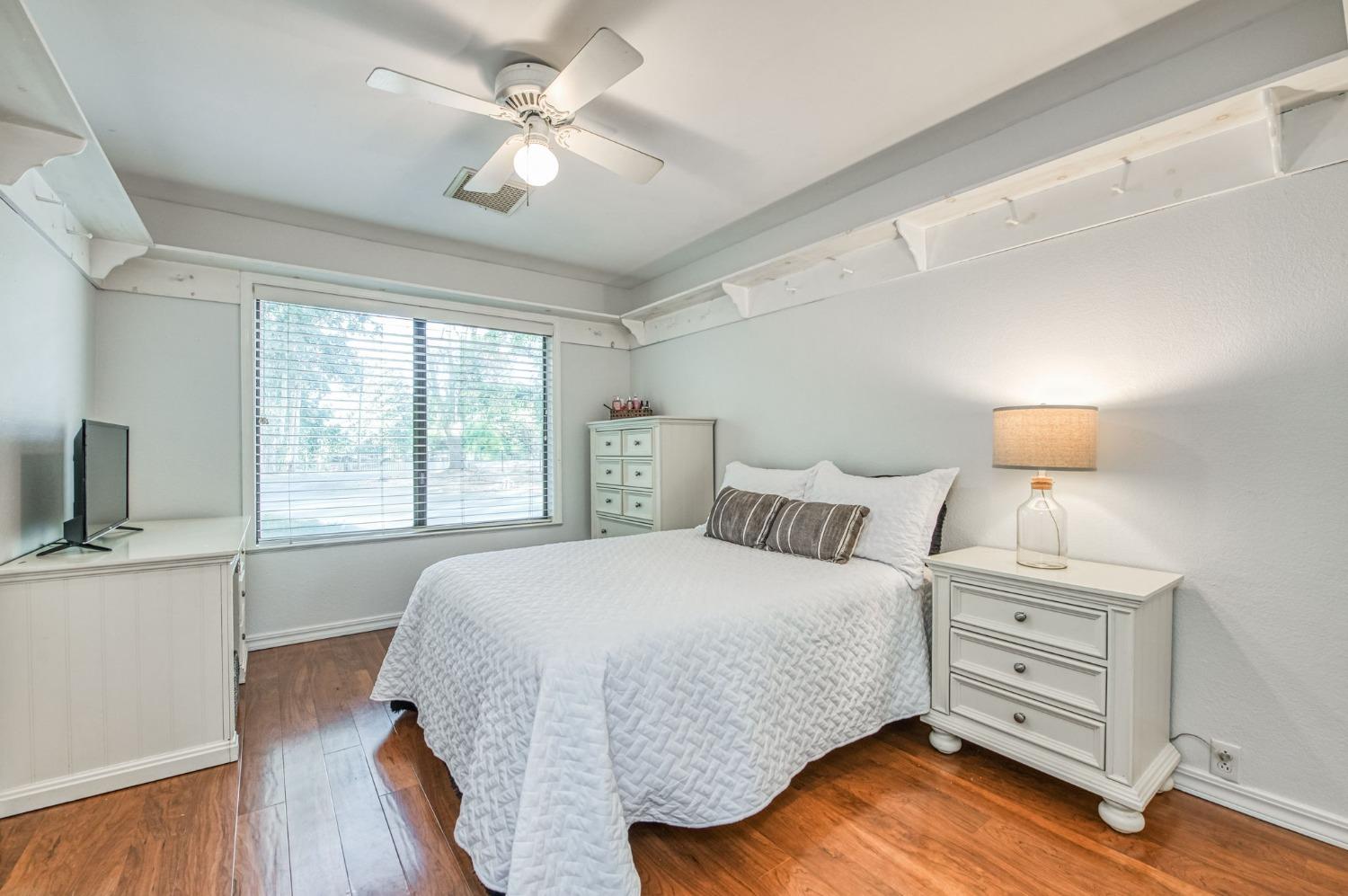 12592 Auberry Road Clovis, CA 93619 - Photo 19 of 65 a bedroom with a bed and a desk with wooden floor