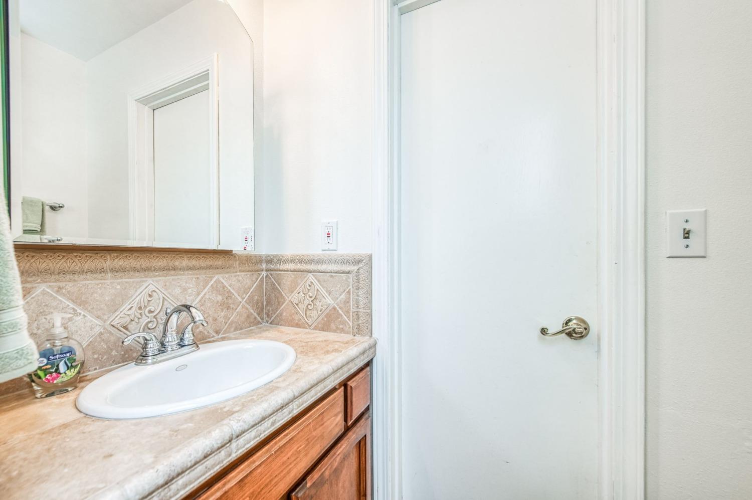 12592 Auberry Road Clovis, CA 93619 - Photo 24 of 65 a bathroom with a granite countertop sink and a mirror