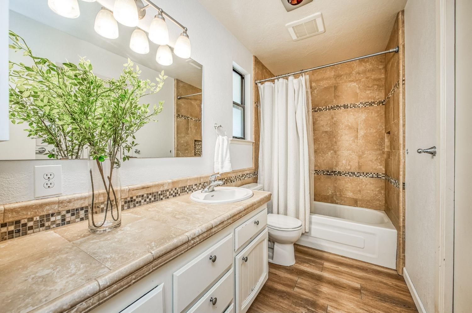 12592 Auberry Road Clovis, CA 93619 - Photo 40 of 65 a bathroom with a granite countertop sink a toilet and shower