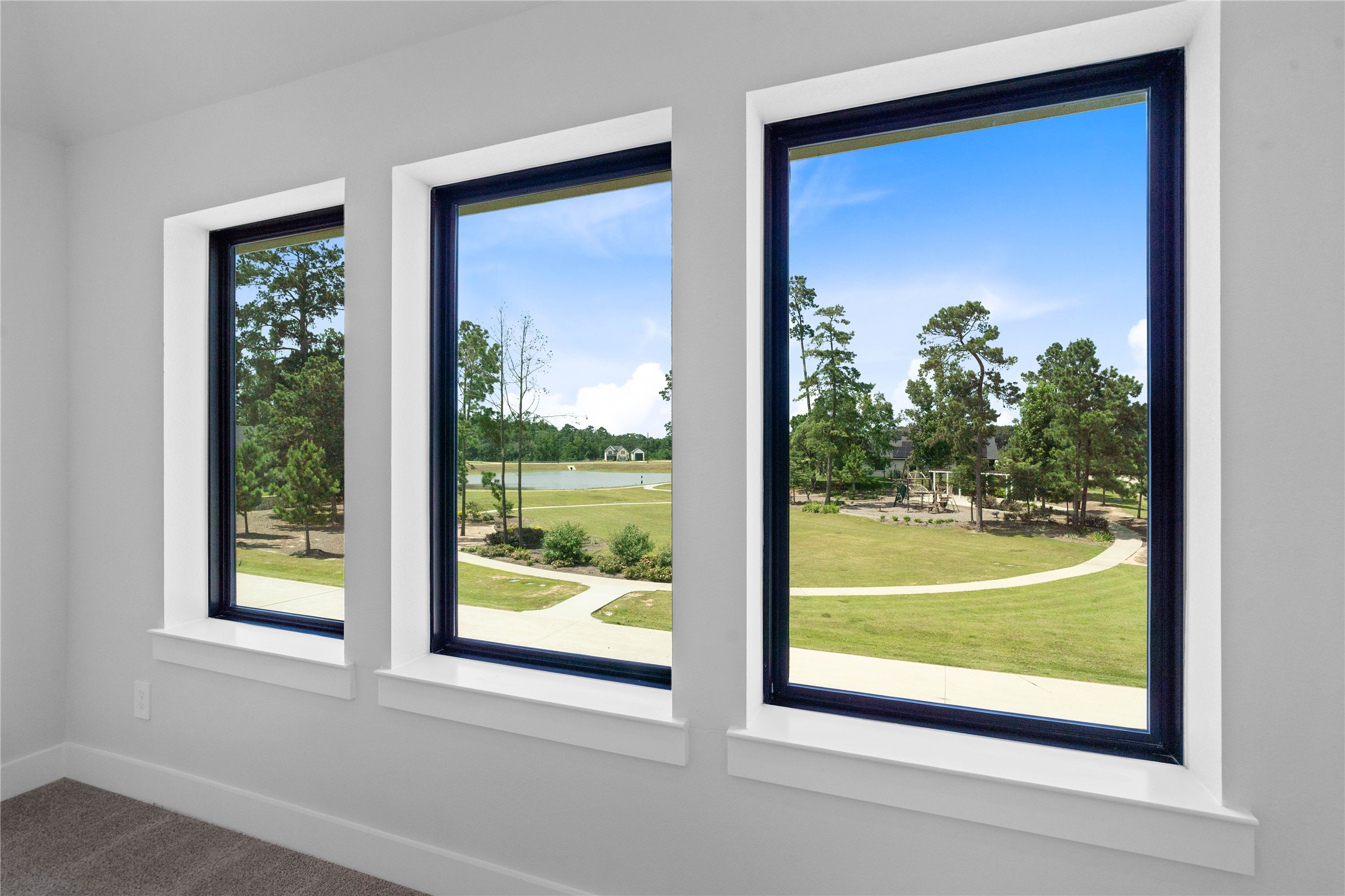 551 Black Bronco Road Magnolia, TX 77354 - Photo 36 of 50 A trio of expansive, picture windows frames stunning, panoramic views of the lush green spaces and serene waterfront nearby. These large windows flood the room with a wealth of natural light, seamlessly connecting the bright interior with peaceful outdoor surroundings.