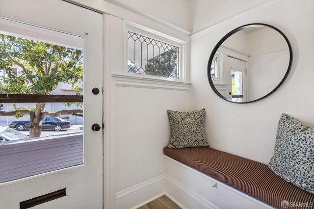 a wooden floor with a large window and a potted plant on table