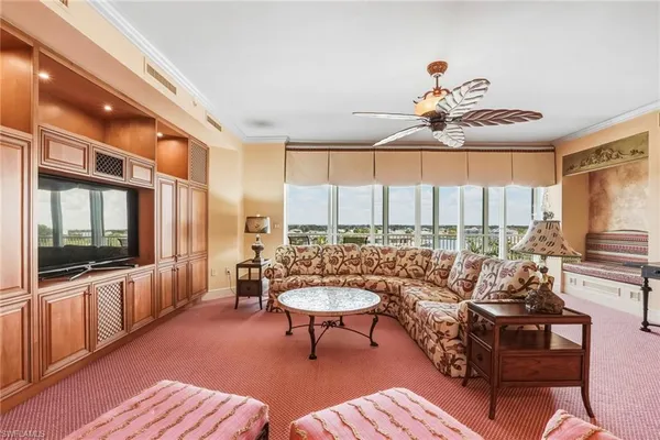a living room with furniture a flat screen tv and a large window