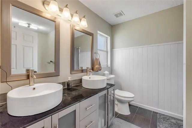 a bathroom with a double vanity sink toilet and a mirror