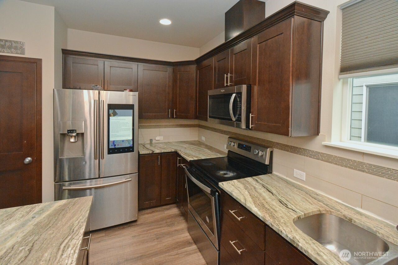 9976 Charles Street Southeast Yelm, WA 98597 - Photo 5 of 30 a kitchen with granite countertop a refrigerator and a sink