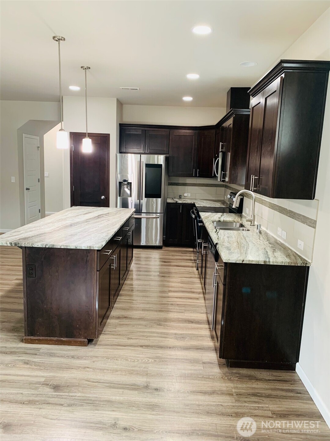 9976 Charles Street Southeast Yelm, WA 98597 - Photo 7 of 30 a large kitchen with stainless steel appliances kitchen island granite countertop a table chairs sink and wooden floor