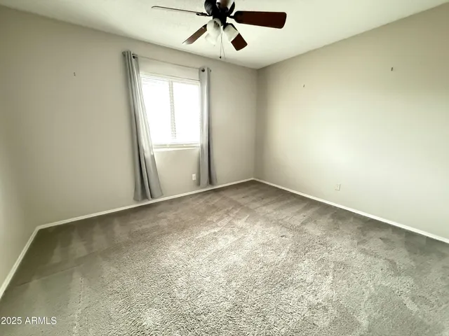 an empty room with a ceiling fan and window